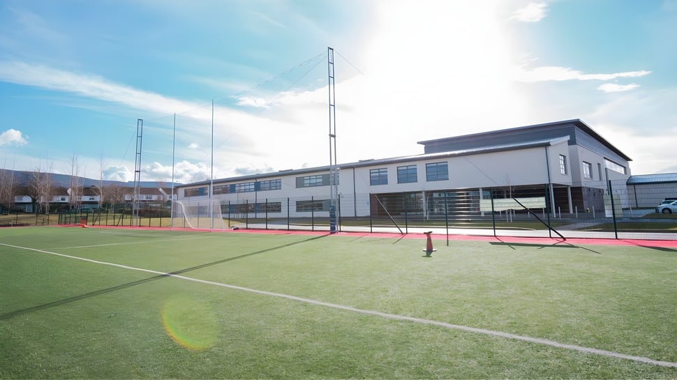Instalación deportiva moderna con pista de tenis frente al edificio de varios pisos en el terreno de la Ballinteer Community School.