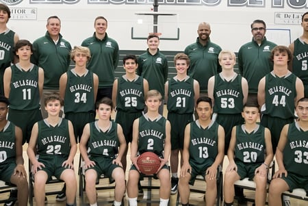 El equipo de baloncesto de la Balmoral State High School posa en camisetas verdes y negras en el gimnasio.