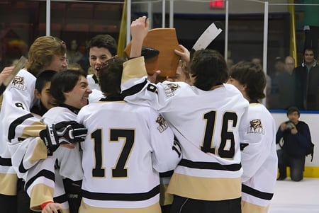 Los jugadores de hockey de la Banff Community High School celebran juntos en el hielo frente a los espectadores.