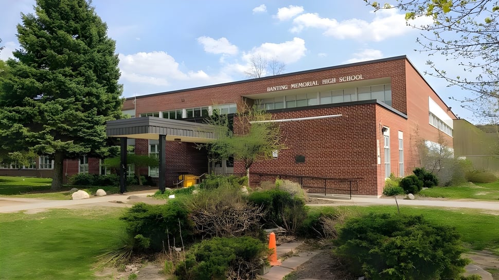 El edificio de ladrillo de la Banting Memorial High School está rodeado de árboles y áreas verdes.