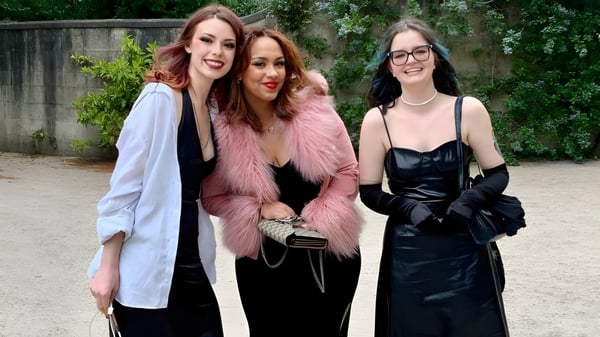 Tres estudiantes de la Bath Academy posan juntas en un área exterior verde.