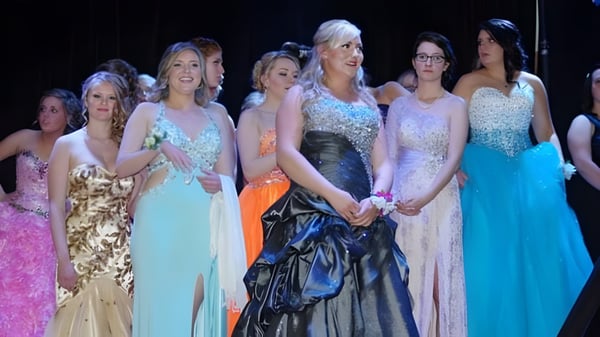 Un grupo de jóvenes mujeres en vestidos de noche formales está en el escenario de la Bawlf School.