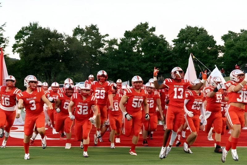 Un grupo de jugadores de fútbol en camisetas rojas corre por el campo en las instalaciones de la Baylor School.