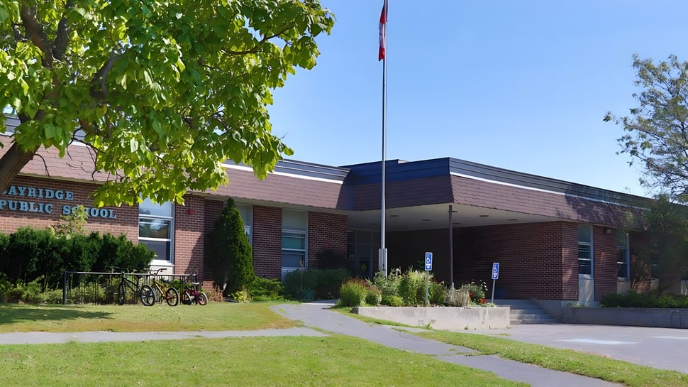 El edificio de ladrillo de la Bayridge Secondary School se encuentra en un área de césped con árboles y un camino pavimentado hacia la entrada.
