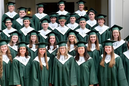 Graduados de la Bayshore Christian School en togas verdes están juntos frente a un edificio con columnas blancas.