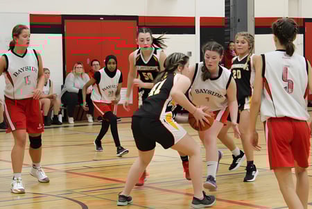 Un grupo de jóvenes jugadoras de baloncesto entrena en la cancha de baloncesto de la Bayside Secondary School.