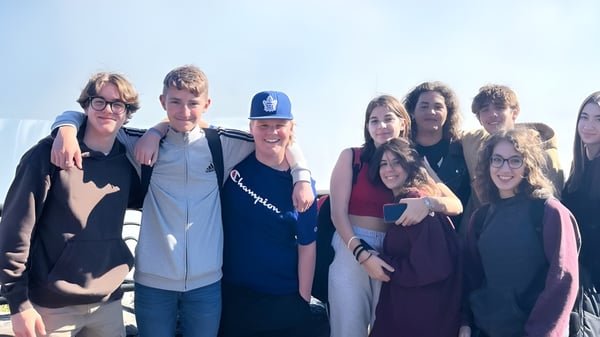 Un grupo de estudiantes se reúne al aire libre en el terreno de la Bayside Secondary School bajo un cielo despejado.