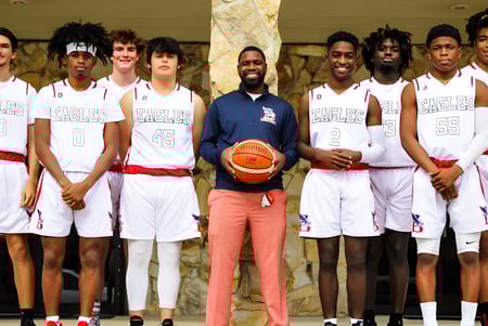 Estudiantes de la Beacon of Hope Christian School llevan camisetas blancas y posan juntos en un gimnasio.