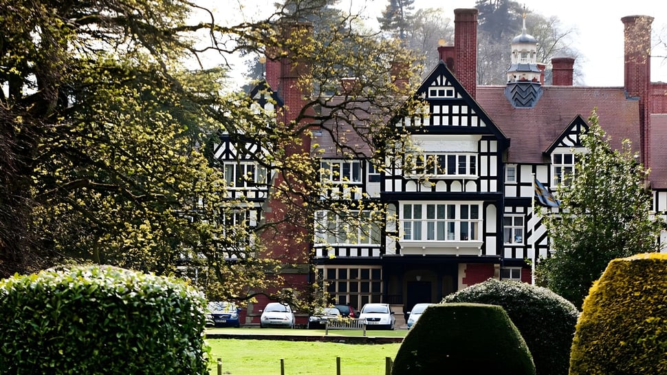 La casa de estilo Tudor con césped cuidado y árboles en el terreno de la Bedstone School.