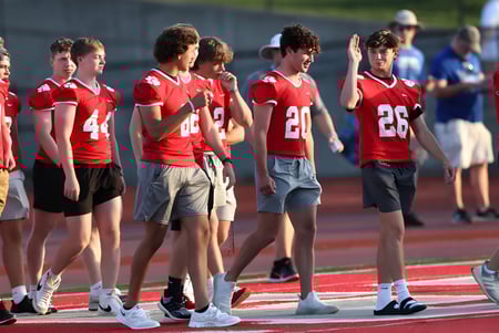 Un grupo de estudiantes de la Beechwood Sacred Heart School está en camisetas rojas en el campo de fútbol frente a los espectadores.