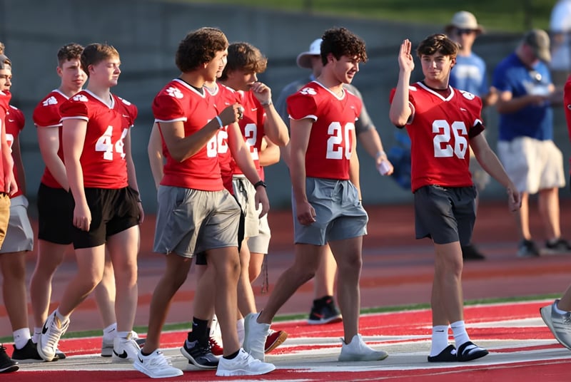 Un grupo de estudiantes de la Beechwood Sacred Heart School está en camisetas rojas en el campo de fútbol frente a los espectadores.