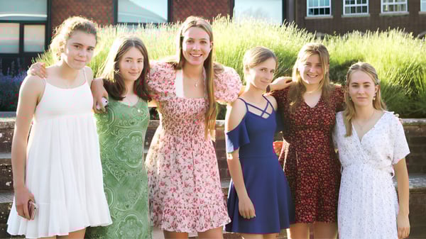 Un grupo de estudiantes está frente a un edificio de ladrillo en el terreno de la Belle River District High School.