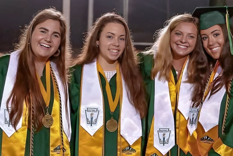 Cuatro estudiantes de la Ben Lippen School posan con ropa de graduación frente a un fondo oscuro.