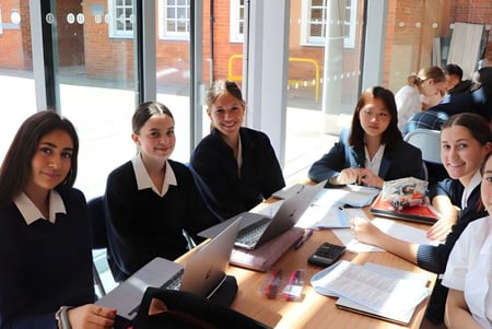 Un grupo de alumnas de la Benenden School está sentado en ropa formal en una mesa en el aula.