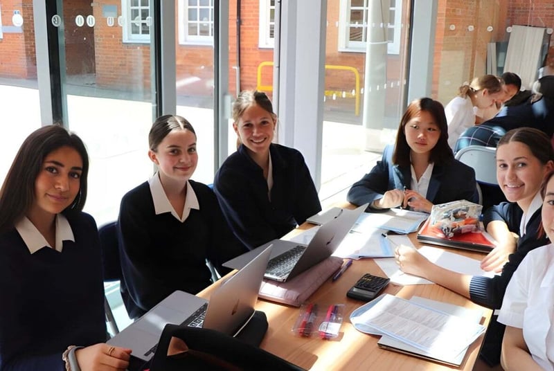 Un grupo de alumnas de la Benenden School está sentado en ropa formal en una mesa en el aula.