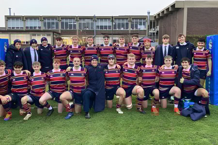 Un grupo de estudiantes que juegan al rugby está en el campo frente a un edificio de ladrillo de la Berkhamsted School.