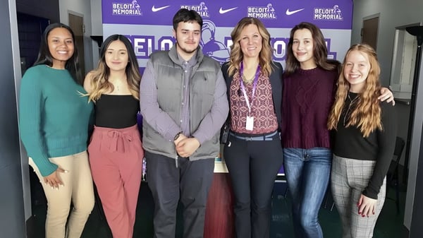 Estudiantes de la Bernice McNaughton High School están de pie frente a un fondo con el logo de Nike y la inscripción Believe in Personal.