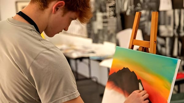 Una estudiante de la Besant Hill School pinta una colorida imagen abstracta en un caballete en un taller.