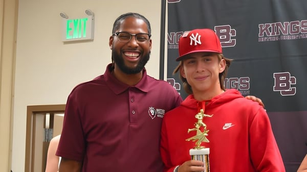 Un hombre con barba y un niño con sombrero rojo posan juntos en un evento deportivo en el campus de las Bethel Christian Schools.