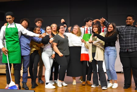 Un grupo de estudiantes de las Bethel Christian Schools está de pie juntos en un escenario frente a un fondo oscuro.
