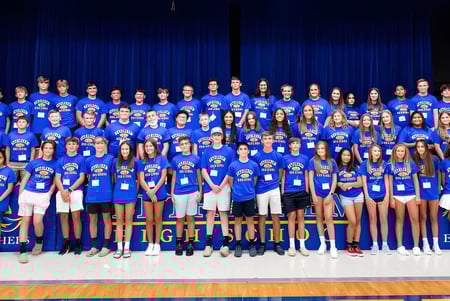 Un grupo de alumnas y alumnos de la Bethlehem High School está junto en un escenario frente a una cortina azul.