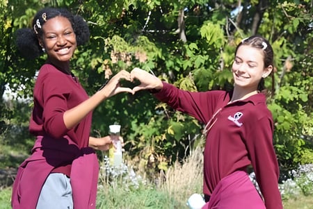 Dos estudiantes de la Beurling Academy forman un corazón con sus manos afuera.