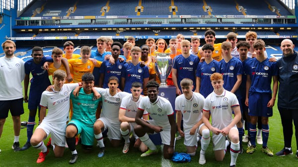 Un gran grupo de futbolistas posan en el campo deportivo de Bexhill College frente a un estadio.