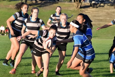 Un grupo de alumnas en ropa deportiva está de pie sobre un campo de césped en el campus del Birkenhead College.