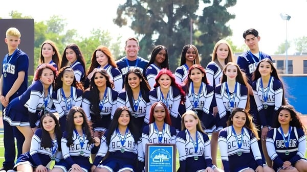 Un grupo de estudiantes de la Birmingham Community Charter High School posan como equipo deportivo frente a un edificio al aire libre.