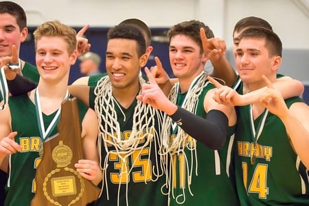 Un grupo de estudiantes masculinos de baloncesto de la Bishop Brady High School celebra con un trofeo después del partido.