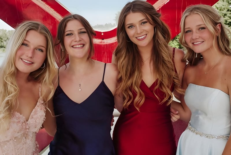 Cuatro estudiantes de la Bishop Carroll High School están juntas frente a un fondo rojo al aire libre.