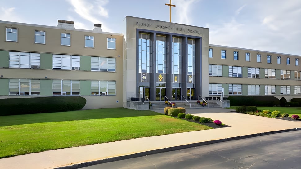 El moderno edificio de varios pisos de la Bishop Kearney High School con una cruz en la fachada está rodeado de césped bien cuidado.
