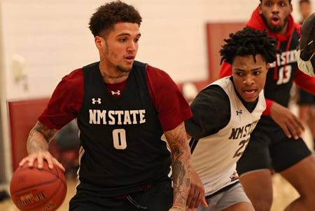 Dos jugadores de baloncesto en uniforme driblan y luchan en la cancha de la Bishop McNally High School.