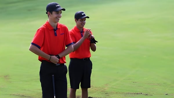 Dos jóvenes están de pie en un campo de hierba en las instalaciones de la Bishop’s Gate Golf Academy.