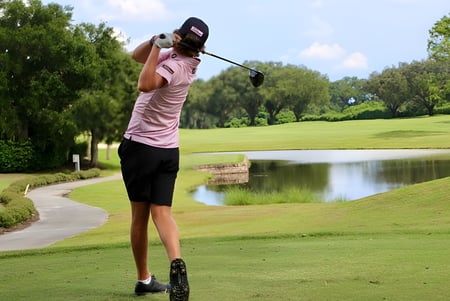 Una mujer hace un swing con un palo de golf en el campo de golf de la Bishop’s Gate Golf Academy.