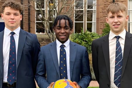 Tres estudiantes en uniformes escolares están frente a un edificio de ladrillo en el campus del Blackrock College.