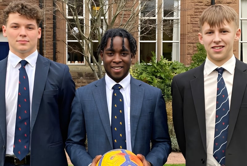 Tres estudiantes en uniformes escolares están frente a un edificio de ladrillo en el campus del Blackrock College.