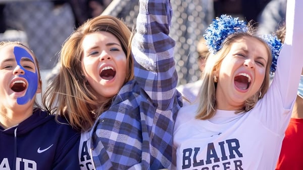 Dos estudiantes de la Blair Academy celebran con los brazos en alto en un evento deportivo.