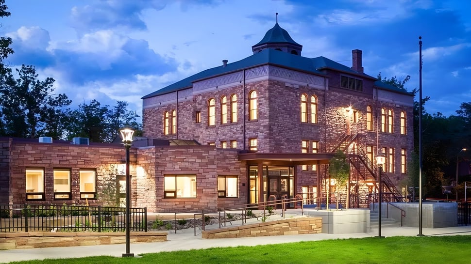 Un gran edificio de piedra con una torre característica se encuentra en el campus de Boulder Valley Public Schools.
