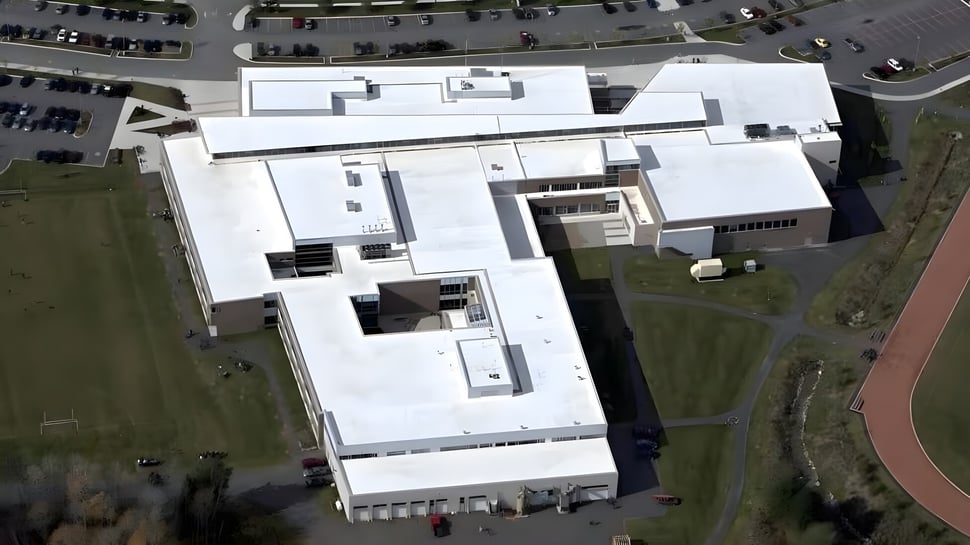 El moderno edificio escolar de la Bracebridge and Muskoka Lakes Secondary School con estacionamiento y áreas verdes al fondo.