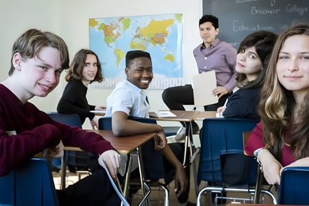 Un grupo diverso de estudiantes está sentado en el aula del Braemar College frente a un mapa del mundo.