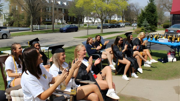 Un grupo de jóvenes estudiantes de Branksome Hall reunidas al aire libre en un prado con togas de graduación.