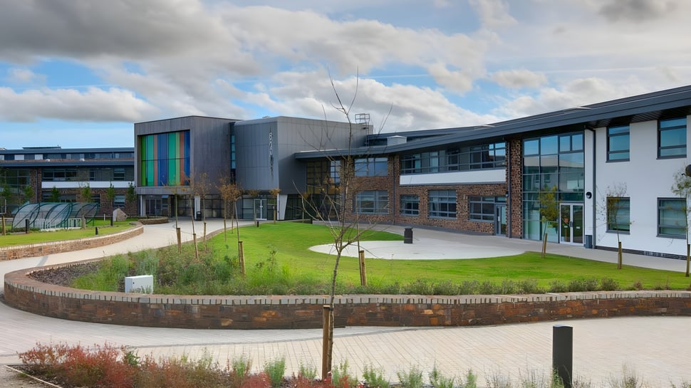 El moderno edificio de varios pisos de la Brannel School con un patio cubierto de hierba y caminos pavimentados en primer plano.