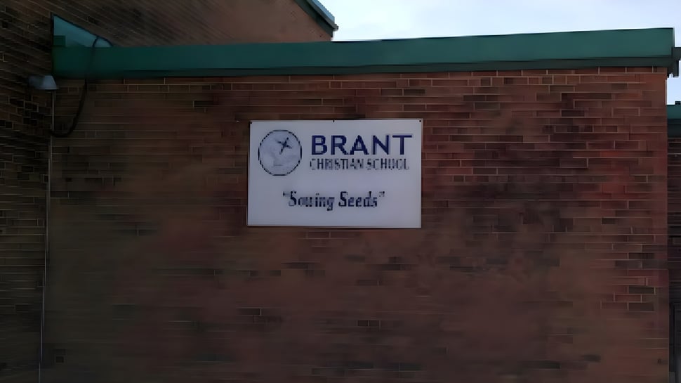 El edificio de ladrillo con techo verde de la Brant Christian School muestra un cartel con la inscripción Sowing Seeds.