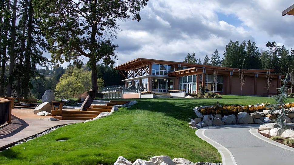 Una casa moderna de madera en el terreno de la Brentwood College School rodeada de áreas verdes y un césped bien cuidado.