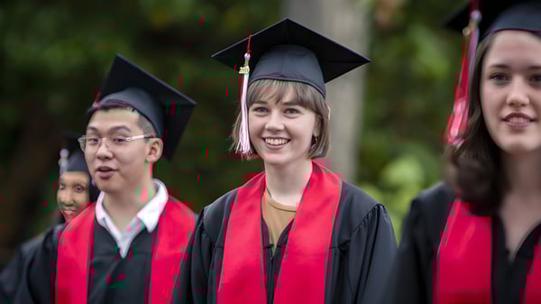 Graduados y graduadas de la Brentwood College School en vestimenta académica frente a un fondo natural.