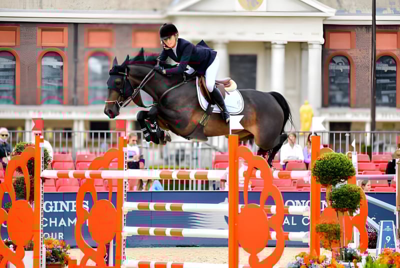 Un jinete salta con un caballo marrón en un torneo en el terreno de la Brentwood School sobre un obstáculo naranja.