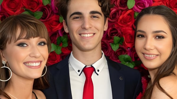 Tres estudiantes frente a un fondo con rosas rojas brillantes en el terreno de la Bribie Island State High School.
