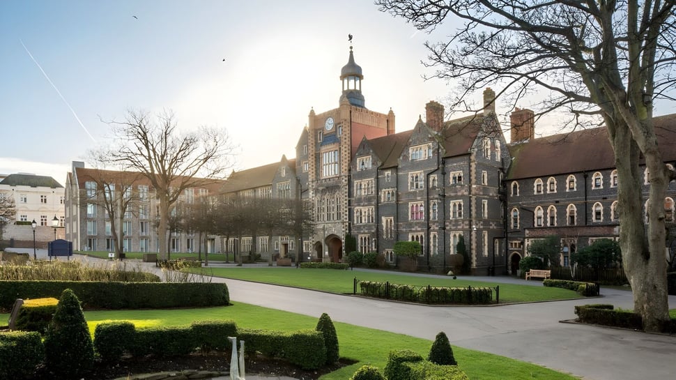 El patio de Brighton College muestra un césped bien cuidado y edificios históricos bajo un cielo despejado.