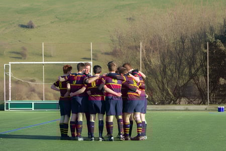 Un grupo de estudiantes está en el campo de deportes de Brighton College rodeado de un paisaje verde.